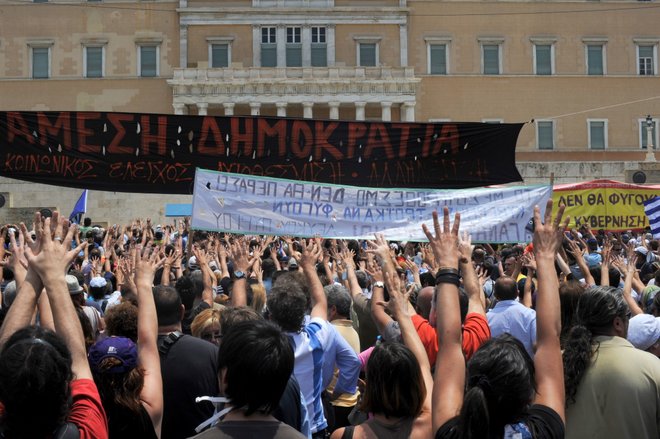 Greeks protesting in front of Parliament using the mountza gesture; Courtesy of Ggia, Wikimedia Commons