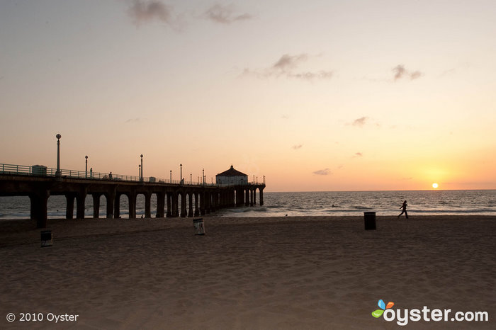 Locals and tourists fish from the pier on Manhattan Beach while they watch the sunset.