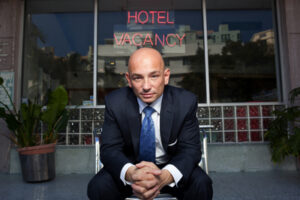 Hotel Impossible's Anthony Melchiorri poses in front of a hotel with some rooms for rent. (Photo Courtesy of the Travel Channel.)